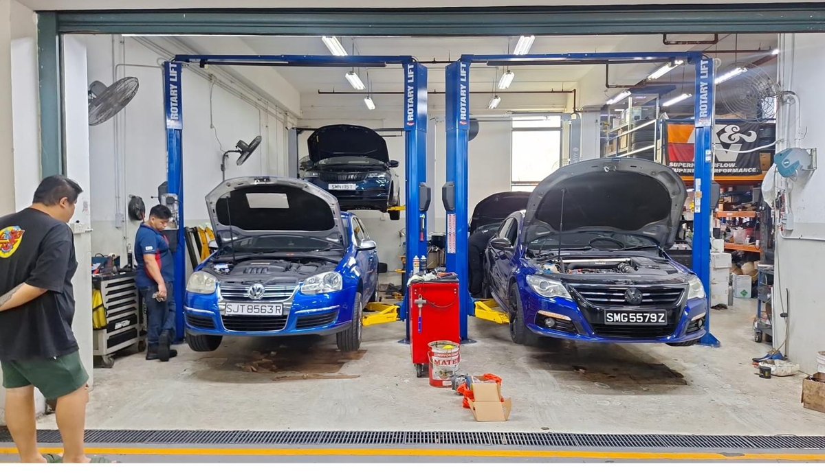 Two cars up on rotary lifts inside MK9 workshop