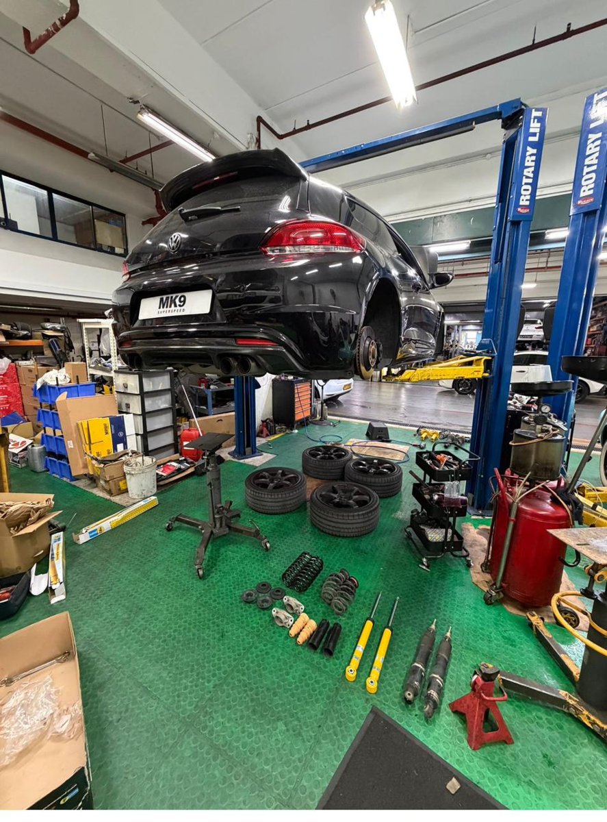 Car on lift with suspension components laid out on the floor